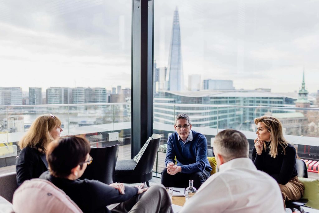 five people working around a table with the London Shard in the background