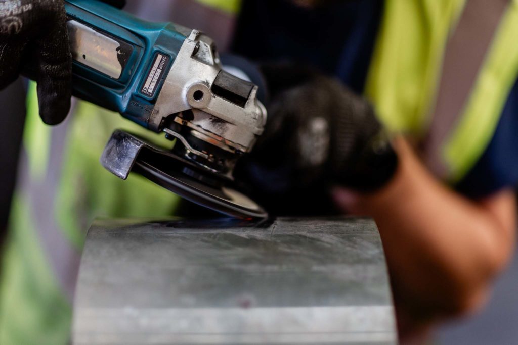 Worker grinding using a power tool and wearing gloves