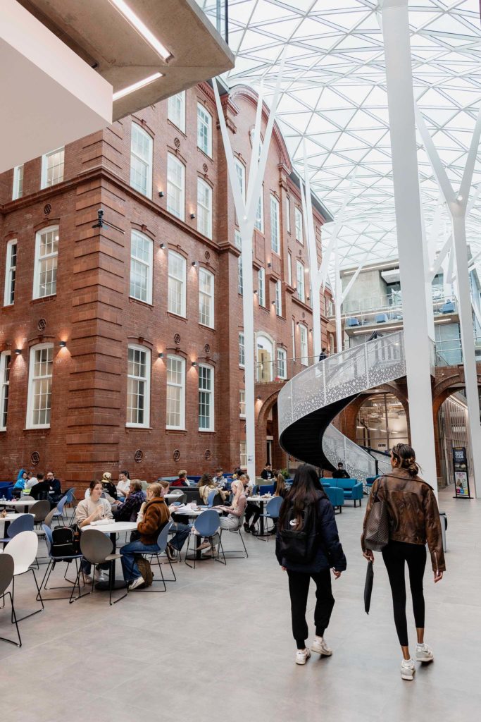 bright building with people sat on tables and people walking