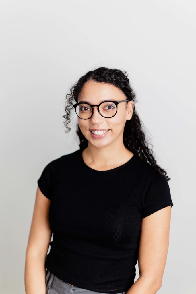 lady in black glasses and black tshirt smiling at the camera