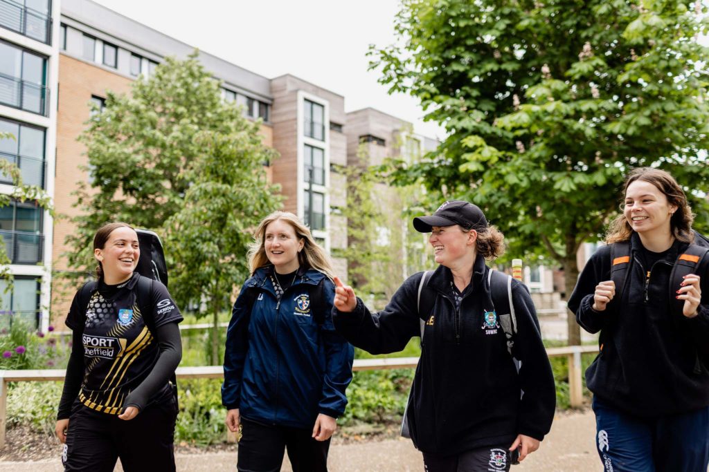 four university students laughing whilst they walk